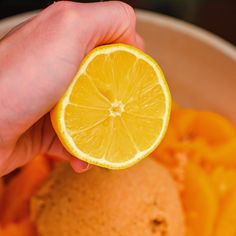 a person holding an orange in their hand over a bowl of food that is half eaten