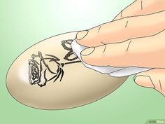 an egg with a spider drawn on it being held up by someone's hand