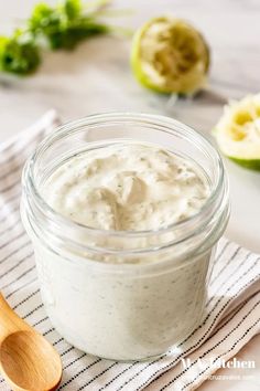 a glass jar filled with yogurt sitting on top of a table next to sliced kiwi