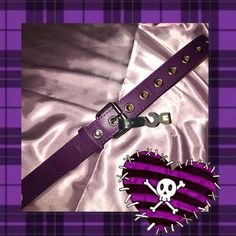 a purple belt with skull and crossbones is laying on a tartan cloth