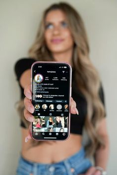 a woman holding up a cell phone with the screen showing an image of herself on it