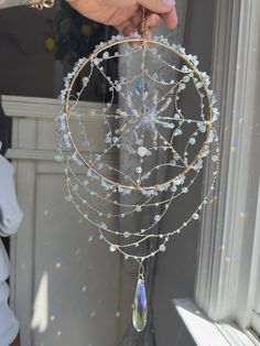 a person is holding a crystal ball ornament in front of a window sill