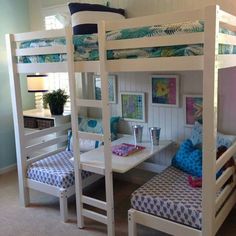 a room with bunk beds and desks in it