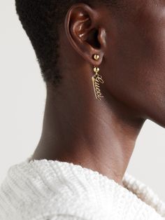 Gucci's gold-tone earrings feature a script version of the house's logo suspended from barbell-inspired posts. Wear yours as part of a stack with dainty studs. Designer Yellow Gold Jewelry With Logo Lettering, Gucci Luxury Drop Earrings, Gucci White Gold Sterling Silver Earrings, Classic Gucci Earrings, Gucci Gold Jewelry For Pierced Ears, Gucci Luxury Sterling Silver Earrings, Luxury Gucci Sterling Silver Earrings, Luxury Gucci Yellow Gold Earrings, Gucci Luxury Pierced Jewelry