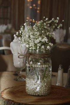 a mason jar filled with baby's breath sitting on top of a wooden table