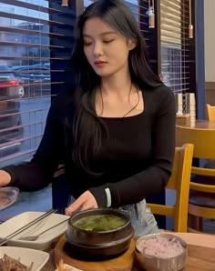 a woman standing in front of a table with food on it and chopsticks