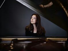 a woman sitting in front of a piano looking up at the sky with her eyes closed