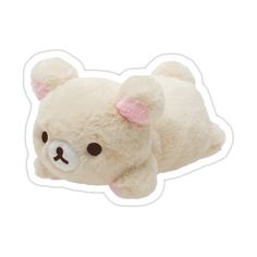 a white teddy bear with pink ears laying down on its side and eyes closed to the camera