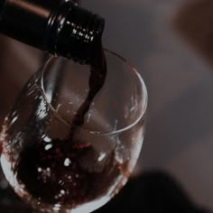 a wine glass being filled with red wine