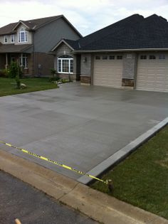 an empty driveway in front of a house with tape taped to the ground and two garage doors