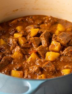 a blue pot filled with meat and potatoes