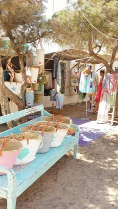 a blue bench sitting under a tree filled with baskets