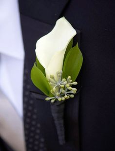 a boutonniere with white and green flowers on it's lapel