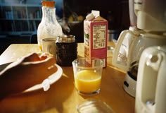 a person is making orange juice on a table with milk and other ingredients around it