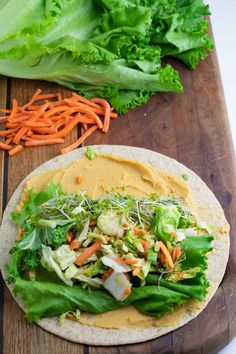 a tortilla filled with lettuce and carrots on a cutting board