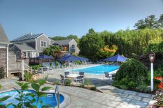 outdoor inground hot tub and pool surrounded by tables with blue umbrellas and gardens. Chatham Massachusetts, Small Waterfall, Martha's Vineyard