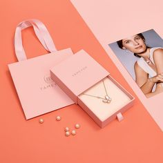 an open pink box with pearls and a necklace in it next to a photo of a woman's face