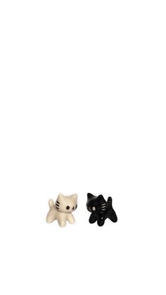 two black and white cat figurines sitting next to each other on a white surface