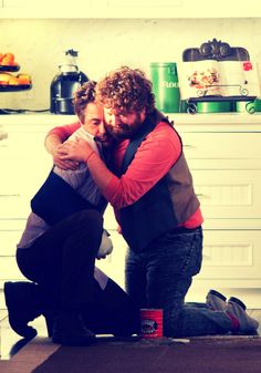 two men hugging each other in the kitchen