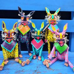 three colorfully painted animal figurines sitting next to each other on a blue bench