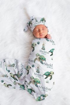 a baby wrapped in a swaddle laying on top of a white blanket