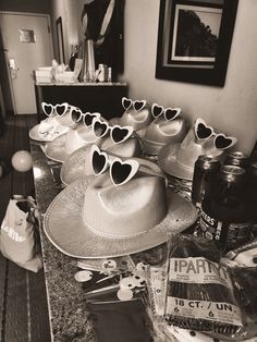 hats and sunglasses are arranged on the counter in this black and white photo, along with other items