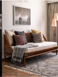 a day bed with pillows on top of it in front of a painting and window