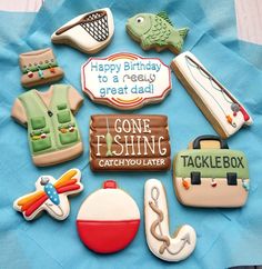 decorated cookies are arranged in the shape of fishing related items on a blue napkin with happy birthday to a really great dad