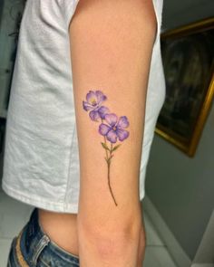 a woman's arm with a purple flower tattoo on the left side of her arm