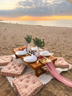 a table set up on the beach with plates and place settings for an outdoor meal