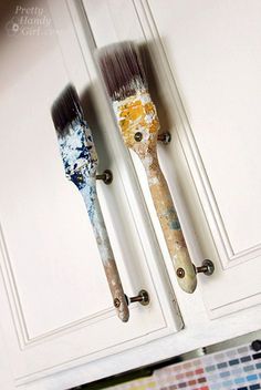 two paintbrushes are hanging on the door handles