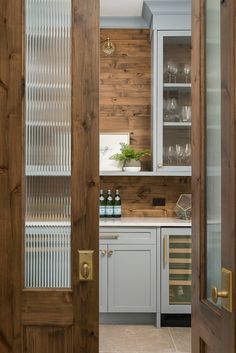 an open door leading to a kitchen with wood paneling and glass doors on both sides