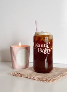 there is a drink in a glass next to a cup with a candle on the table