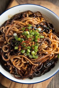 a bowl filled with noodles and vegetables on top of a wooden table