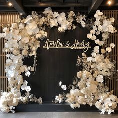 the entrance to an event decorated with white flowers and gold lettering that reads ardlen & henry