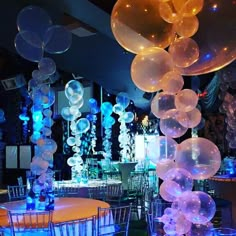 balloons are floating in the air over tables and chairs at a party with blue lights