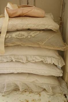 a stack of pillows sitting on top of each other in front of a wall with peeling paint