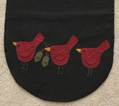 three red birds on black fabric with green leaves in the center and two yellow ones at the bottom