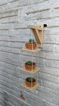 three tiered wooden planter with succulents in it on the side of a building