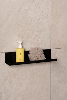 a black shelf with a yellow bottle and towel on it next to a white wall