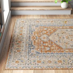 an orange and blue area rug on the floor in front of stairs with bookshelves