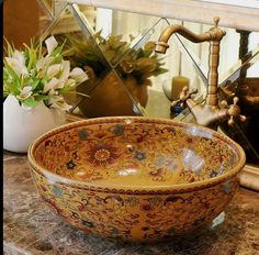 a bowl shaped sink sitting on top of a counter next to a vase with flowers