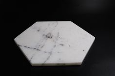 a white marble hexagonal object on a black surface