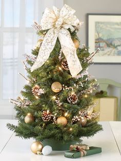 a small christmas tree decorated with gold and white ornaments