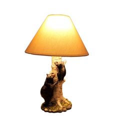 two cats sitting on top of each other under a lamp that has a shade on it