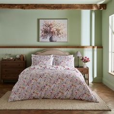 a bed in a room with green walls and wooden flooring next to a painting on the wall