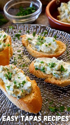 four bread bowls filled with food on top of a glass plate next to another bowl