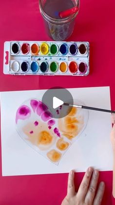 someone is painting a heart with watercolors