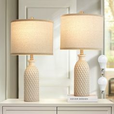 two lamps sitting on top of a white dresser