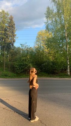 a woman standing in the middle of an empty street with her hat on top of her head